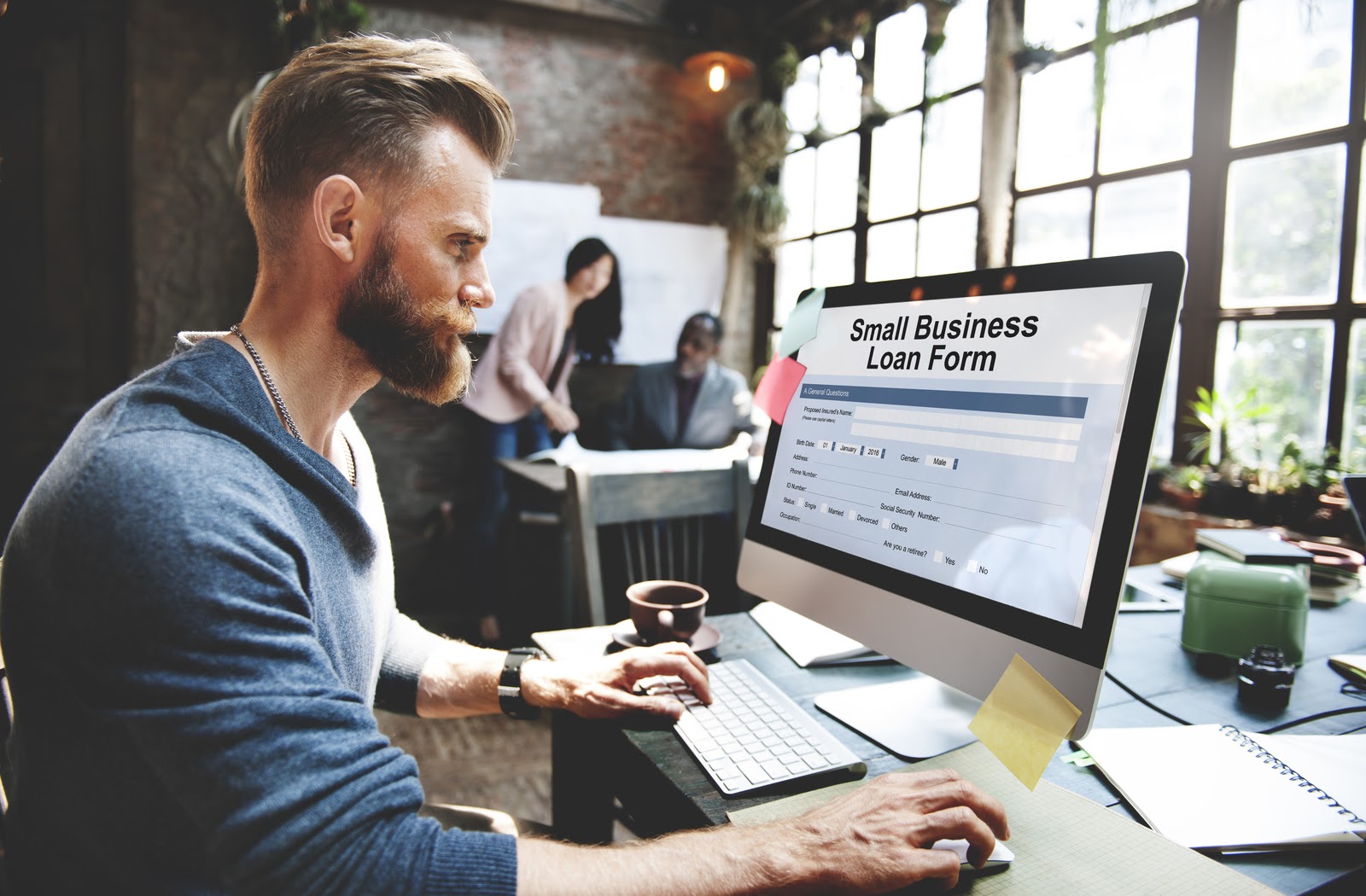 Young man on his computer filling out small business loan form.