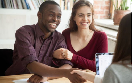 Young happy couple shaking hands with advisor after taking out loan