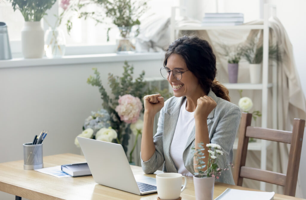 Young professional women sitting at desk with laptop happy about business loan news