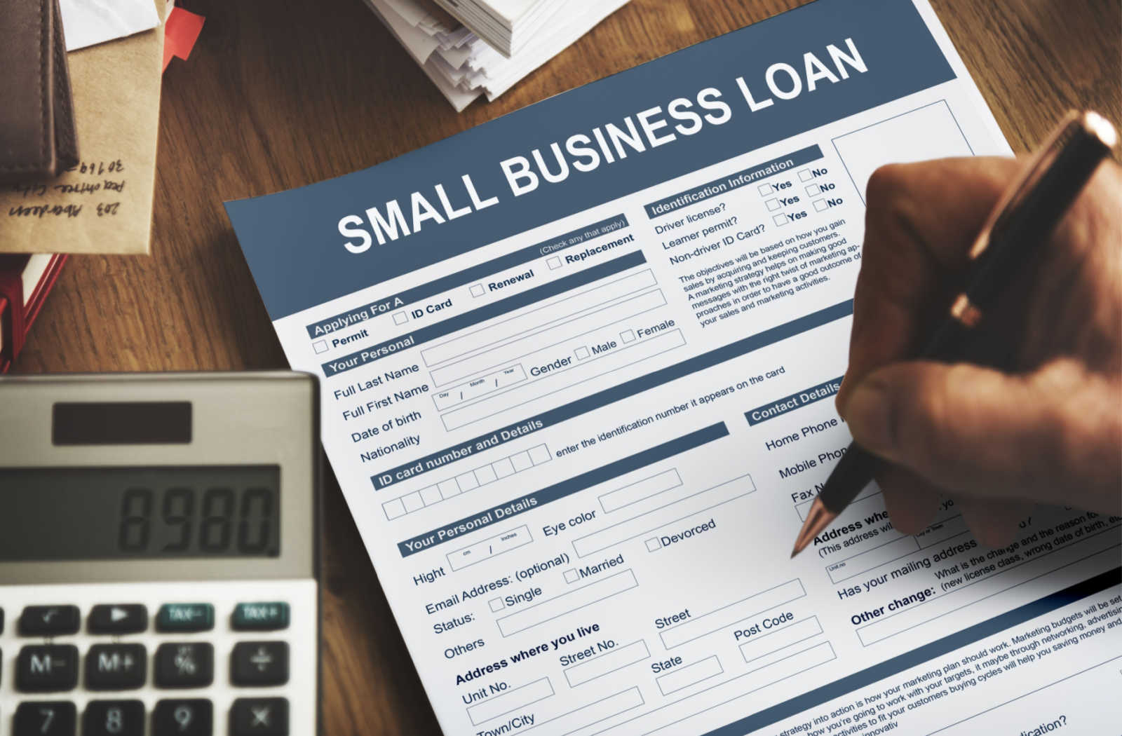 Person filling out a small business loan form with a pen