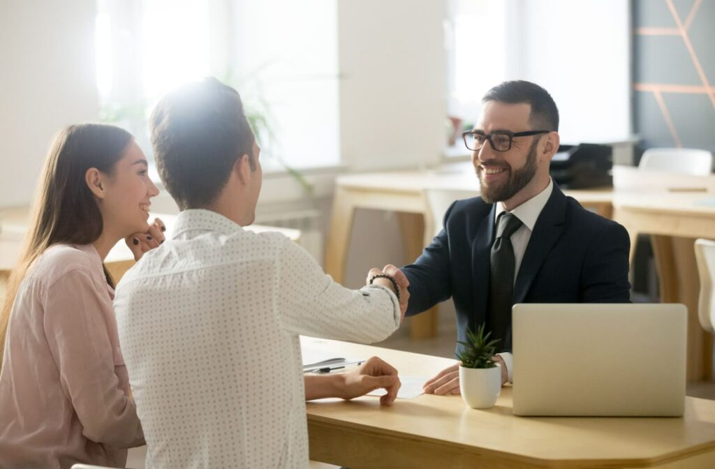 A happy young couple talking to a loan officer in an office about a business loan.