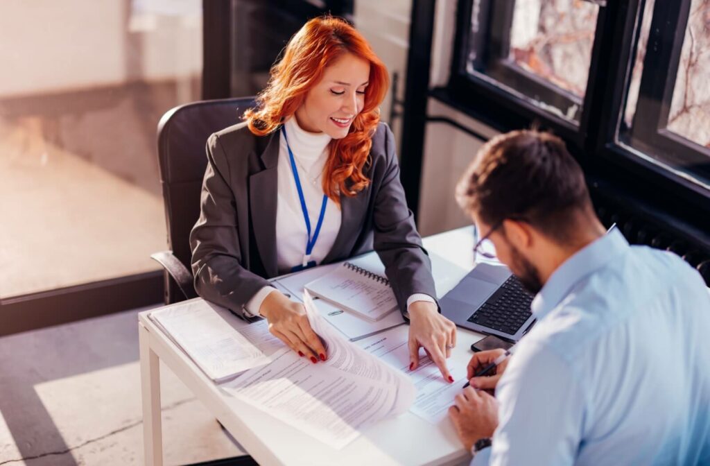  A person sitting at a desk with a professional lender and going over contract information before signing.